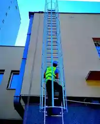 Montaż stalowej drabiny ewakuacyjnej KOST PRO na elewacji budynku przez ekipę montażową